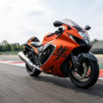 Une moto sportive Suzuki Hayabusa orange et noire roulant à vive allure sur un circuit de course.