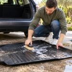 un homme nettoie son tapis de coffre en caoutchouc
